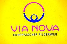 Logo für VIA NOVA Europäischer Pilgerweg auf gelbem Hintergrund, mit einer stilisierten violetten und blauen Figur mit erhobenen Armen innerhalb eines Halbkreises über dem Text.